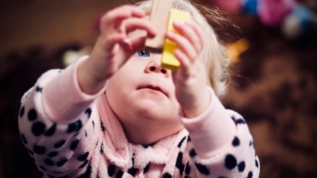 Infant engaging with colorful blocks as part of cognitive activities for infants, enhancing problem-solving and motor skills.