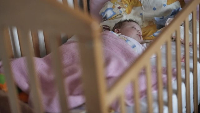 Newborn baby peacefully sleeping in a cozy bassinet, wrapped in a pink blanket, emphasizing safe and comfortable sleep practices for infants.