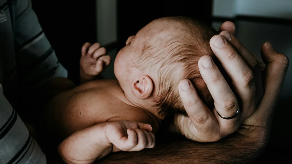 Parent supporting a newborn's head and neck in a safe and secure holding position, demonstrating one of the essential ways to hold a newborn.