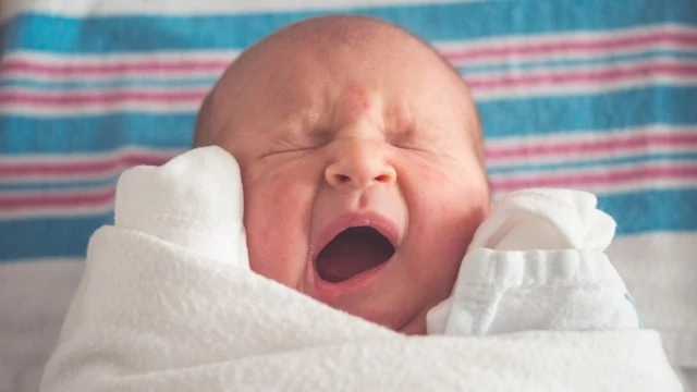Newborn yawning during a wake window, highlighting signs of tiredness and the importance of managing Newborn Wake Windows.