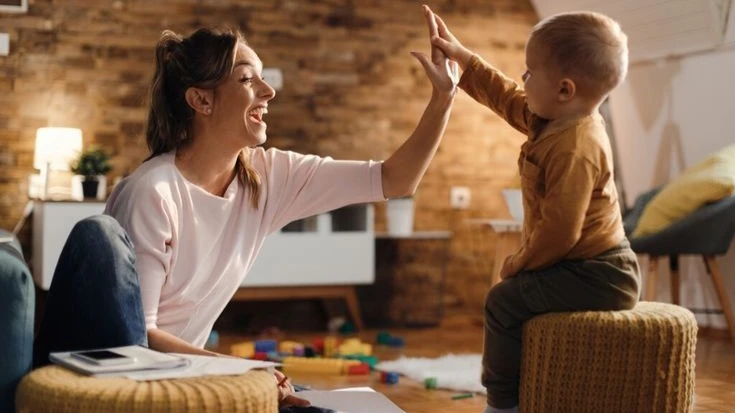 A mother and her young child share a joyful high-five, reinforcing trust and respect. Setting boundaries for kids helps them learn cooperation and confidence.