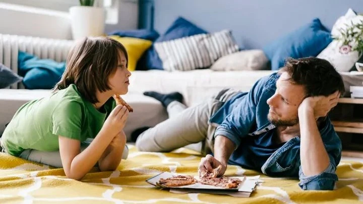A father and his child share a meaningful conversation over pizza, highlighting the importance of open communication and rules for teenagers.
