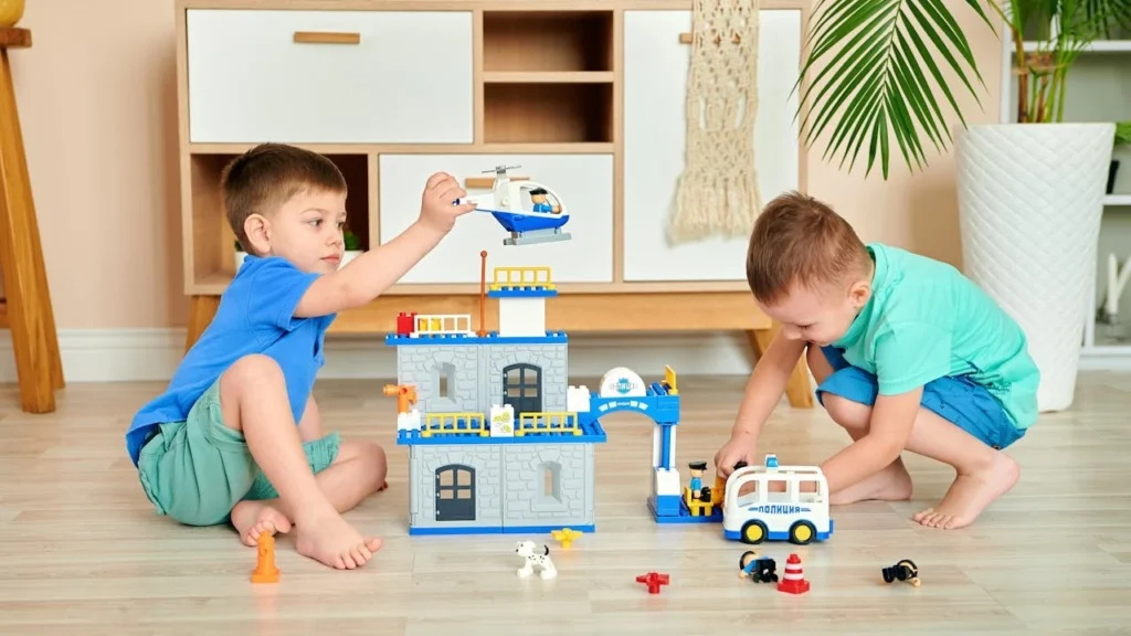 Toddlers playing with building blocks and vehicles as part of fine motor skills activities for toddlers.