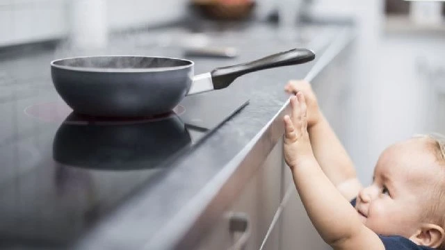 Toddler reaching for hot pan on stove—showing a real-life scenario that often leads to one of the most common childhood injuries: burns.